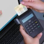 Osoba przykłada smartfon do laptopa w celu weryfikacji tożsamości
