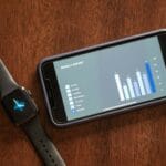 Smartfon i smartwatch z tygodniowym raportem zdrowia na drewnianym stole