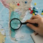 Dłoń z lupą nad mapą Ameryki Południowej, z zaznaczoną Argentyną