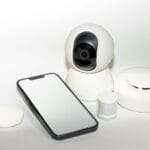 Zestaw urządzeń zabezpieczających smart home obok smartfona