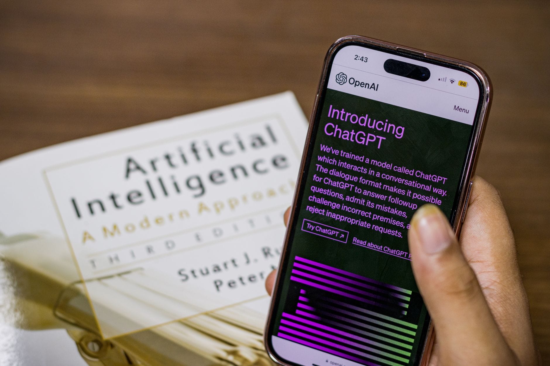Smartfon z otwartą aplikacją ChatGPT trzymany nad podręcznikiem o AI