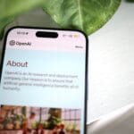 Smartfon z otwartą stroną OpenAI na tle rozmytej zieleni
