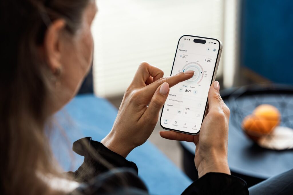 Kobieta steruje ustawieniami sauny w aplikacji na smartfonie