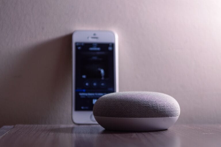 Smartfon i głośnik smart home na drewnianym stole